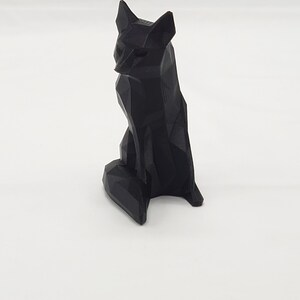 May include: A black, geometrically designed fox figurine. The fox is sitting with its tail curled around its legs.
