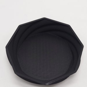 May include: A black octagonal bowl with a textured surface. The bowl is made of a hard plastic material.