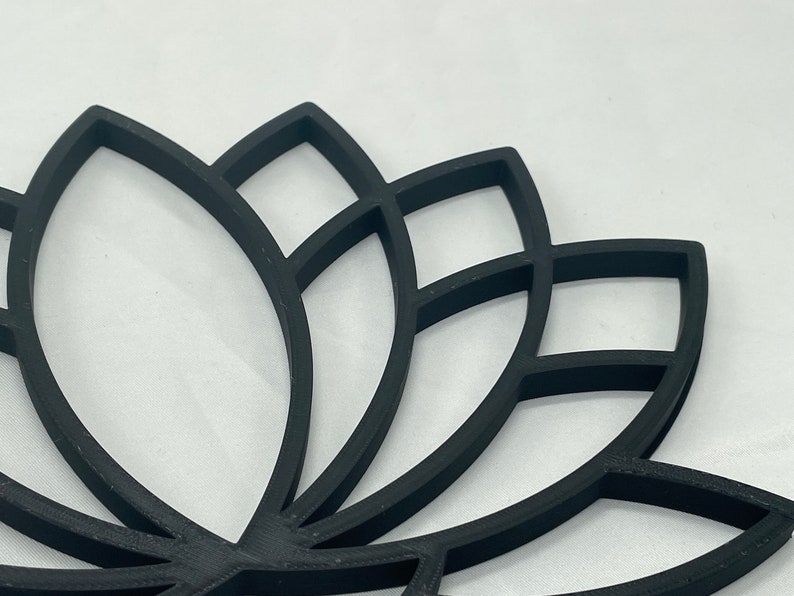 May include: Black lotus flower design wall decor. The design is made of multiple layers of thin black metal, creating a 3D effect.