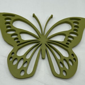 May include: A green wooden butterfly wall decor with a cutout design. The butterfly has a detailed wing pattern with multiple circles and lines.