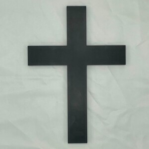 May include: A black wooden cross with a simple design. The cross is made of a single piece of wood and has a smooth finish.