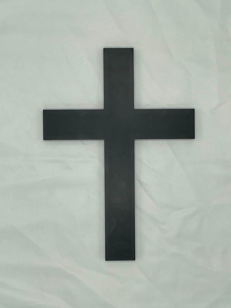 May include: A black wooden cross with a simple design. The cross is made of a single piece of wood and has a smooth finish.