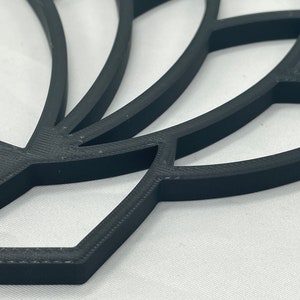 May include: A black 3D printed lotus flower design with intricate details. The design is made up of multiple layers of petals, creating a layered effect.