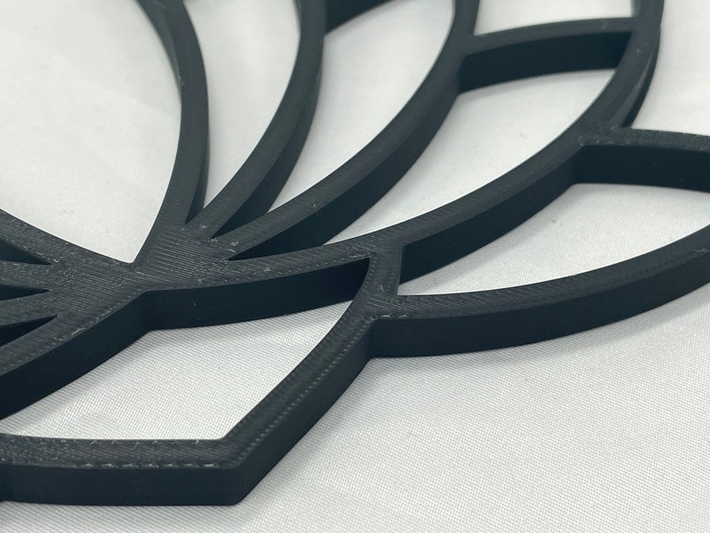 May include: A black 3D printed lotus flower design with intricate details. The design is made up of multiple layers of petals, creating a layered effect.