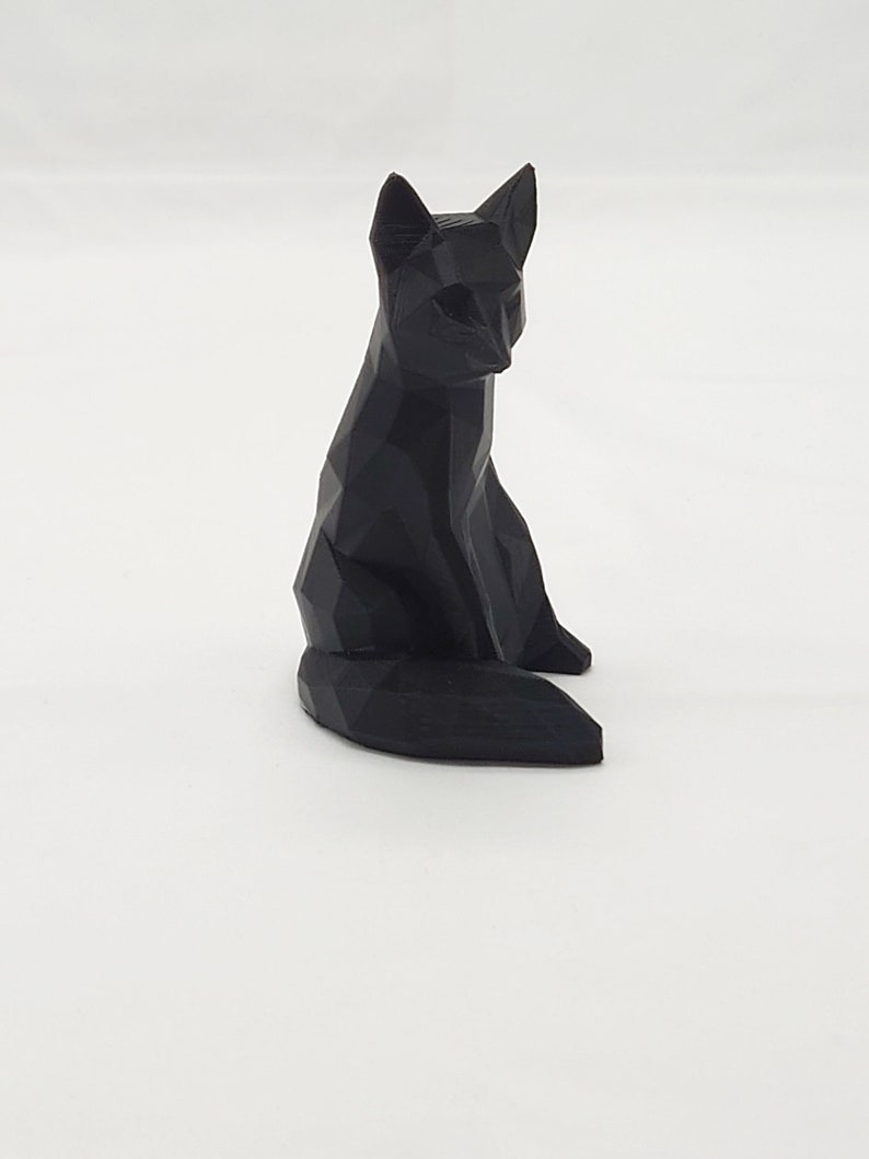 May include: A black, geometrically designed fox figurine. The fox is sitting with its tail curled behind it.