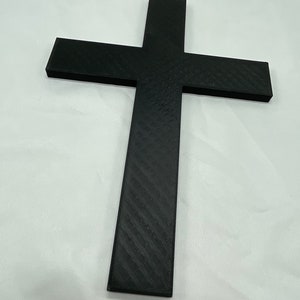 May include: A black cross made of plastic with a textured surface.