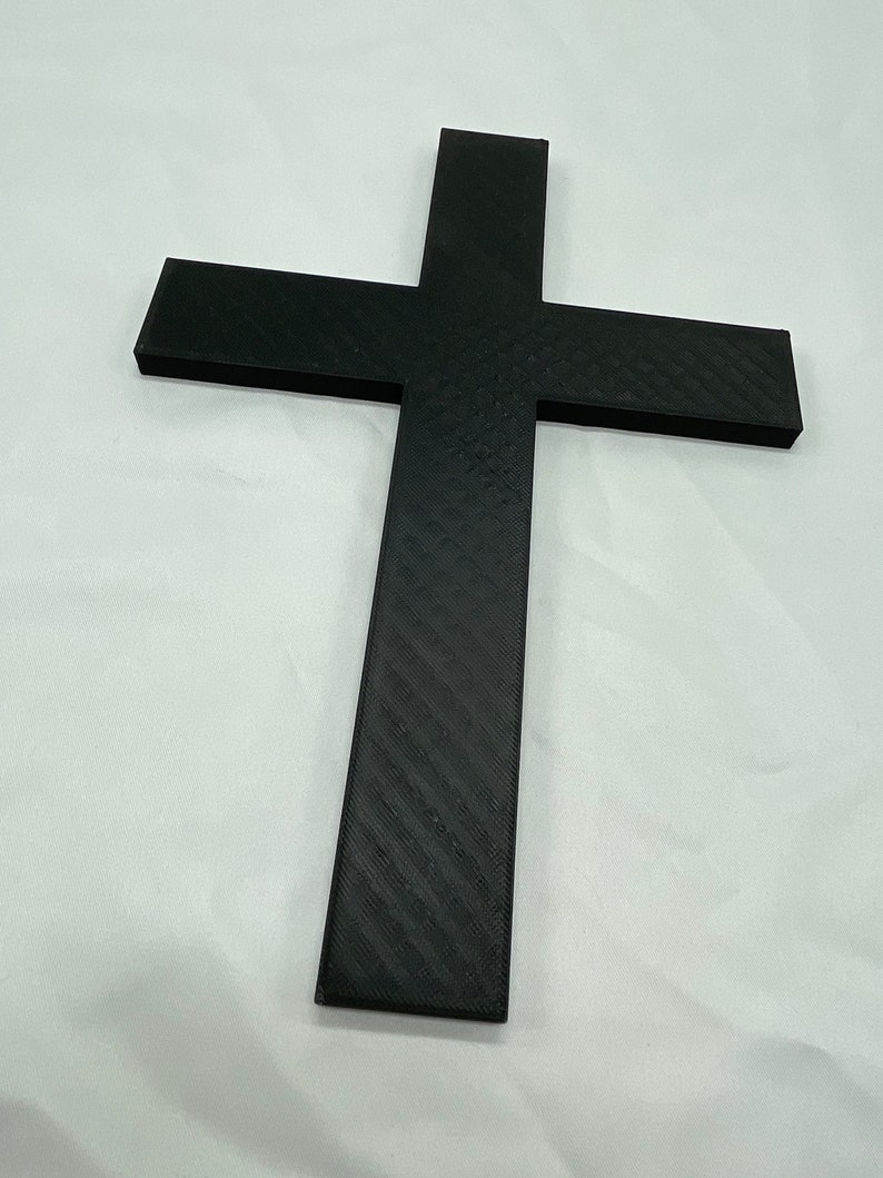 May include: A black cross made of plastic with a textured surface.