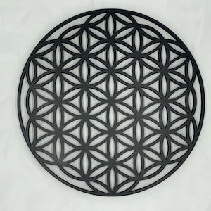 May include: A black wooden wall hanging in the shape of a flower of life mandala. The intricate design features overlapping circles and geometric patterns.