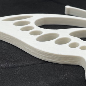 May include: White plastic butterfly wall decor with a layered, 3D design. The butterfly has a series of oval cutouts in the wings.