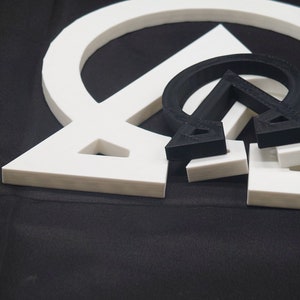 May include: Three white geometric shapes, a circle, a triangle, and a square, are stacked on top of each other. The shapes are made of a thick, white material and have a smooth, glossy finish.