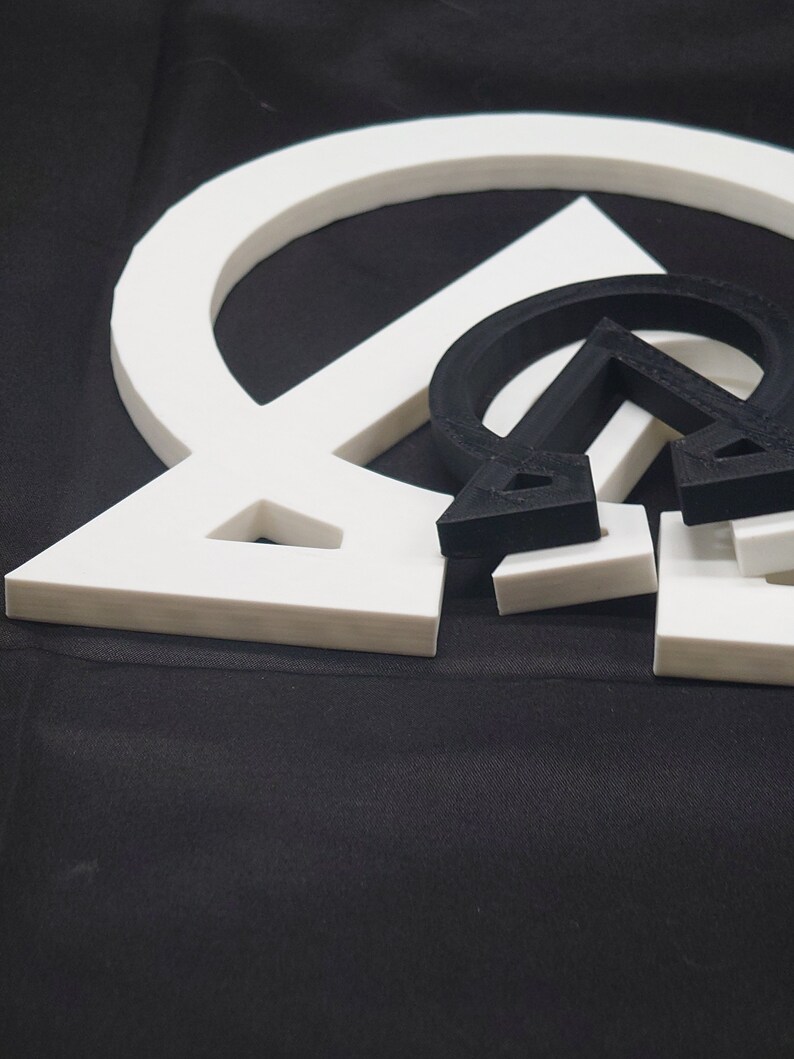 May include: Three white geometric shapes, a circle, a triangle, and a square, are stacked on top of each other. The shapes are made of a thick, white material and have a smooth, glossy finish.
