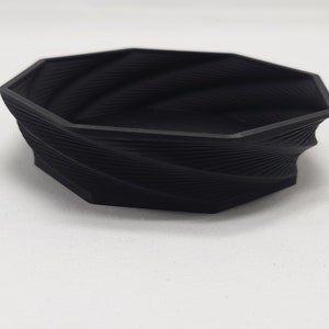 May include: A black, octagonal, 3D printed bowl with a swirling, textured design.