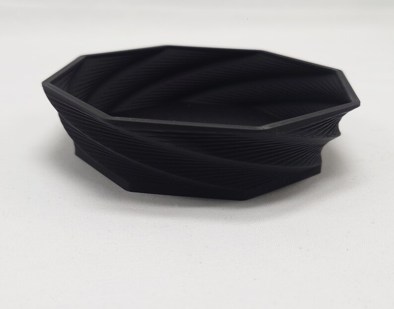 May include: A black, octagonal, 3D printed bowl with a swirling, textured design.