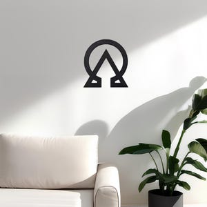 May include: Black metal wall decor featuring a stylized symbol with a circle and a triangle. The symbol is mounted on a white wall.