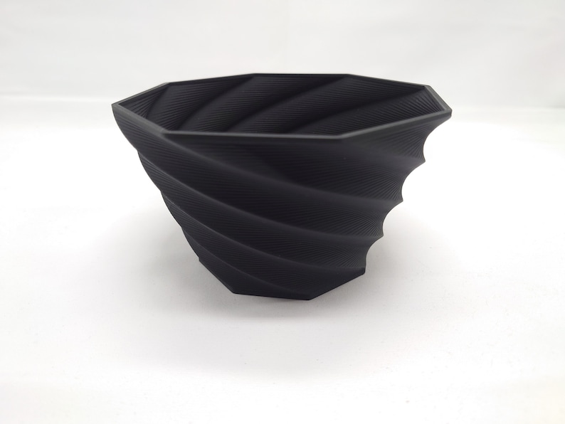Pu&ograve; includere: Un vaso da fiori nero di forma ottagonale con un design a spirale e texture. Il vaso &egrave; realizzato in un materiale liscio e opaco.