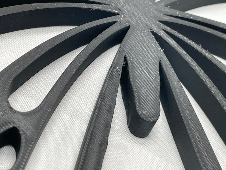 May include: Close-up of a black, 3D printed, geometric design with a starburst pattern. The design has a textured surface and appears to be made of plastic.