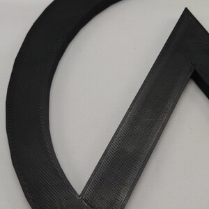 May include: Close-up of a black 3D printed object with a circular and triangular shape.