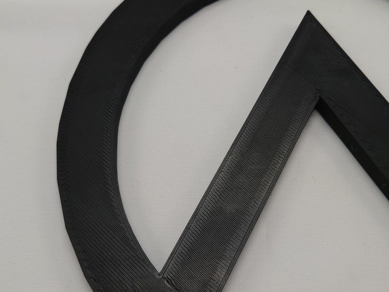May include: Close-up of a black 3D printed object with a circular and triangular shape.