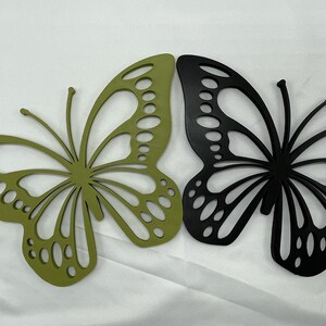 May include: Two decorative butterfly wall sculptures, one green and one black, with intricate cut-out designs.