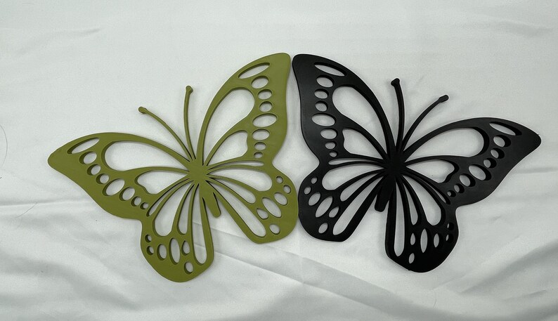 May include: Two decorative butterfly wall sculptures, one green and one black, with intricate cut-out designs.