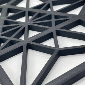 Pu&ograve; includere: Un design geometrico nero composto da triangoli, creando un effetto 3D. Il design &egrave; realizzato con un materiale nero spesso ed &egrave; probabilmente un'appendice da parete o un pezzo decorativo.