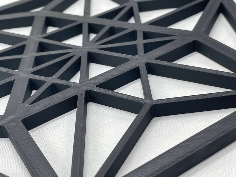 Pu&ograve; includere: Un design geometrico nero composto da triangoli, creando un effetto 3D. Il design &egrave; realizzato con un materiale nero spesso ed &egrave; probabilmente un'appendice da parete o un pezzo decorativo.