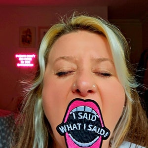 May include: A pink and black embroidered patch with a large mouth and the text "I SAID WHAT I SAID!"