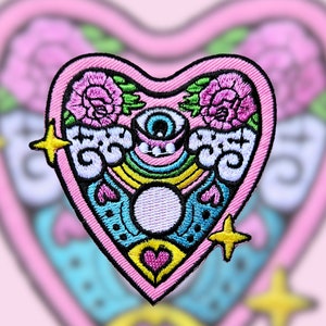 May include: Pink heart-shaped embroidered patch featuring a rainbow, clouds, a single eye, and two roses. The patch has yellow stars on either side.