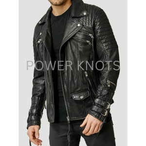 May include: Black leather motorcycle jacket with zippered pockets, a quilted design on the sleeves, and a buckle detail on the cuffs. The jacket has a zipper closure and a collar.