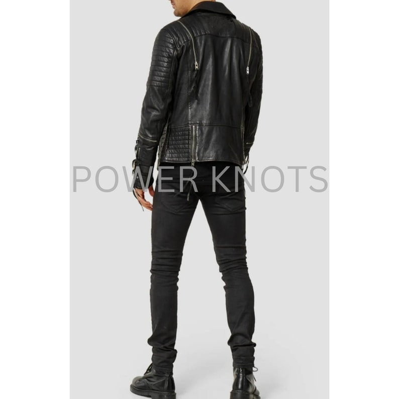 May include: Black leather jacket with zipper details and a quilted pattern. The jacket has a stand-up collar and a zipper closure. The model is wearing black jeans and black boots.