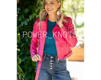 May include: A bright pink leather jacket with a zip fastening and a belt at the waist. The jacket has a  "POWER_KNOTS" logo on the front.