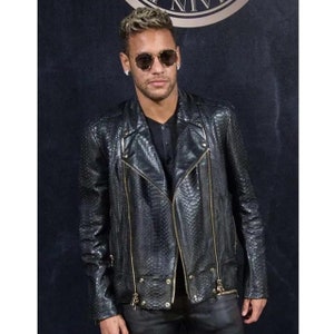 May include: A man wearing a black leather jacket with a snakeskin pattern and gold zippers. He is also wearing a black t-shirt, black jeans, and sunglasses.