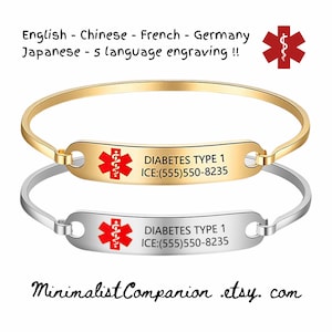 Op de afbeelding: Twee medische waarschuwingsarmbanden, één goudkleurig en één zilverkleurig, elk met een rood medisch symbool en de tekst "DIABETES TYPE 1 ICE:(555)550-8235". De armbanden zijn in vijf talen gegraveerd.
