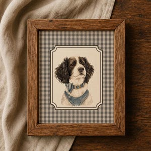 May include: A framed print featuring a portrait of a brown and white spaniel dog wearing a blue denim harness and a matching bow tie. The artwork is set against a gray and white gingham background and enclosed in a rectangular wooden frame.