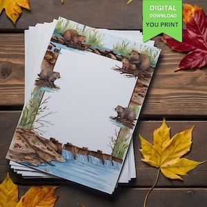 Könnte beinhalten: Ein Stapel weißes Papier mit einer Aquarellillustration von Bibern in der Nähe eines Wasserfalls und eines Baches. Das Bordürendesign zeigt Biber, Wasser und Blätter. Der Text "DIGITAL DOWNLOAD YOU PRINT" befindet sich in einem grünen Banner. Herbstblätter sind verstreut.