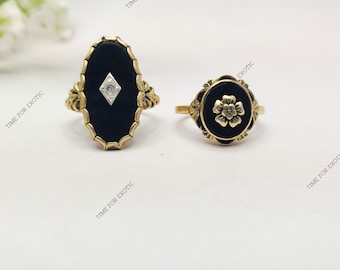 May include: Two gold rings with black onyx settings. One ring features a single diamond, while the other has a floral design.