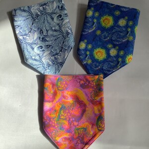 May include: Three fabric bandanas with different patterns. One is blue with a swirling pattern, one is blue with a starry night pattern, and one is pink with a marbled pattern.