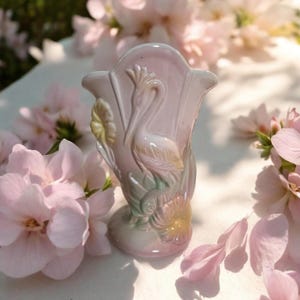 May include: A white ceramic mug with a black handle and the text "But First, Coffee" in a bold, black font. The mug is set against a blurred background, suggesting a cozy setting.