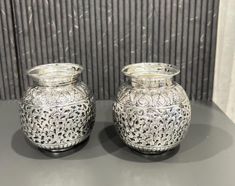 May include: Two silver decorative jars with intricate floral designs. The jars are round and have a smooth, polished finish.