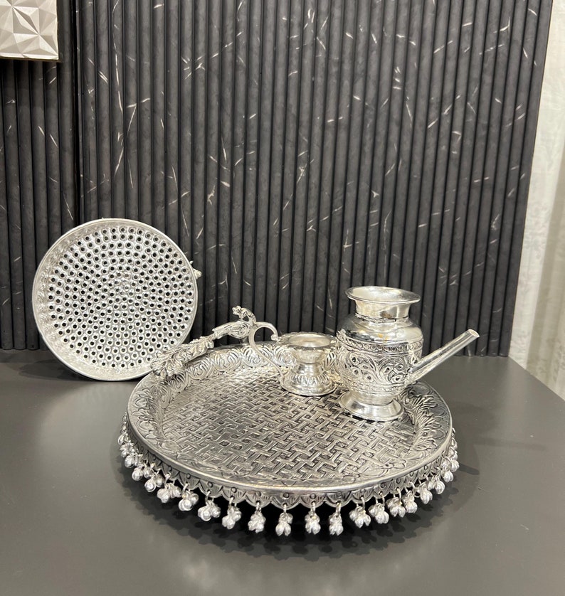 May include: A silver tray with a decorative design and a beaded border. The tray contains a silver pitcher, a small silver bowl, and a silver plate with a perforated design.