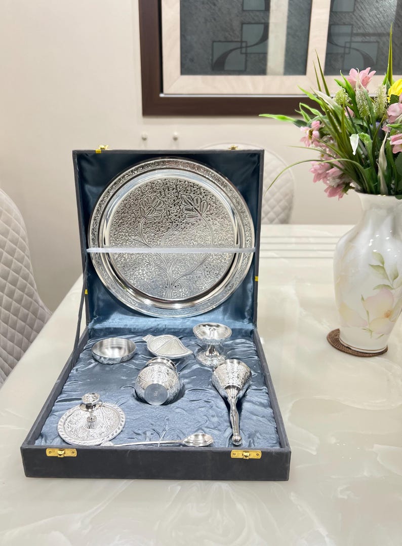May include: A silver serving set in a black velvet box. The set includes a large plate, a small bowl, a spoon, a small cup, and a small pitcher.