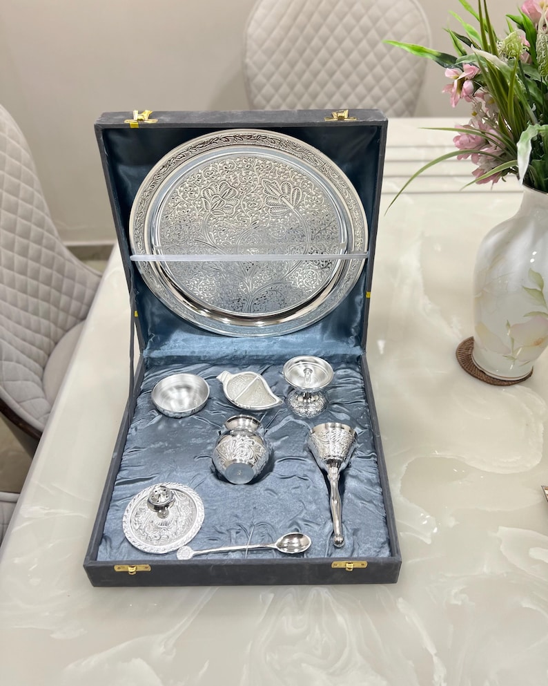 May include: A silver serving set in a black velvet lined box. The set includes a large round tray, a small bowl, a sugar bowl, a creamer, a pitcher, a spoon, and a lidded dish.