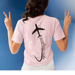 May include: A pink t-shirt with a black airplane graphic and the text "airplane mode" on the back.