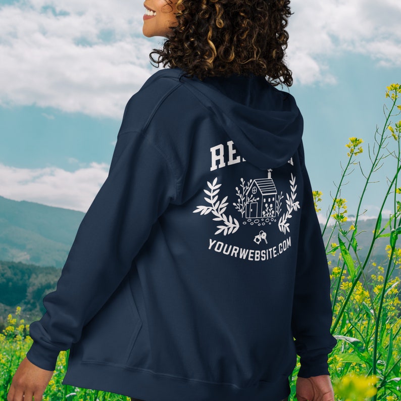 May include: A navy blue zip-up hoodie with a white graphic on the back. The graphic features a house with a wreath, keys, and the text "YOURWEBSITE.COM".