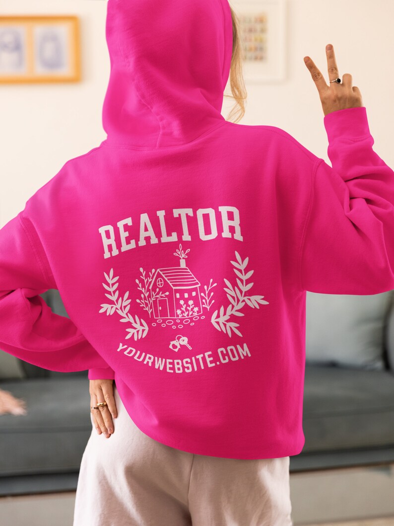 May include: A pink hoodie with the word "REALTOR" printed on the back, along with a house illustration and the text "YOURWEBSITE.COM".