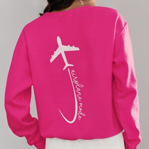 May include: A pink sweatshirt with a white airplane graphic and the text "airplane mode" on the back.
