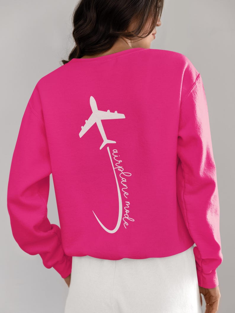 May include: A pink sweatshirt with a white airplane graphic and the text "airplane mode" on the back.