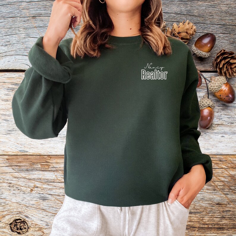 May include: A dark green sweatshirt with the text "Nancy Realtor" in white lettering on the front.
