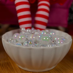 May include: A white ceramic bowl filled with iridescent white and clear round ornaments.
