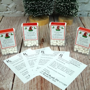 May include: Four clear plastic containers filled with white pills, each labeled with a red and white label featuring a cartoon elf and the word "Prescription." The prescriptions are for "Snow Day Snipples," "Elf Teleportation Lag," "Elf Flu," and "Christmas Blahs."